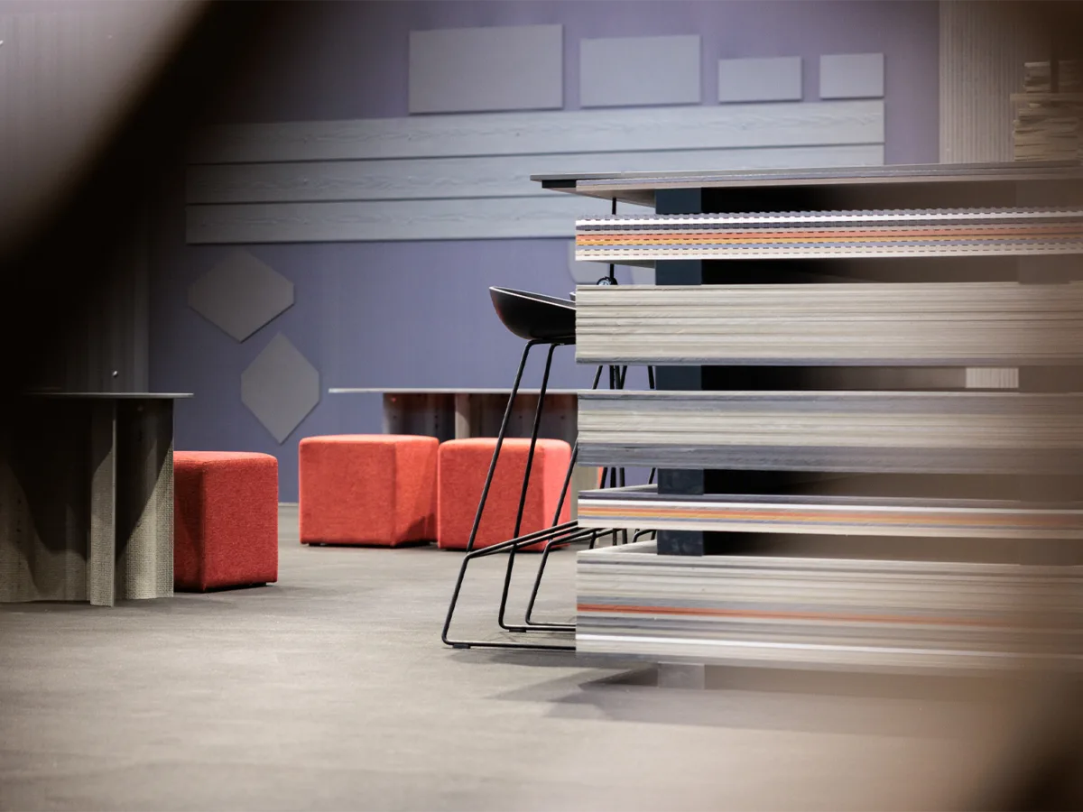 Materialtresen aus horizontal geschichteten Faserzementplatten in verschiedenen Farben mit Lounge-Bereich im Hintergrund