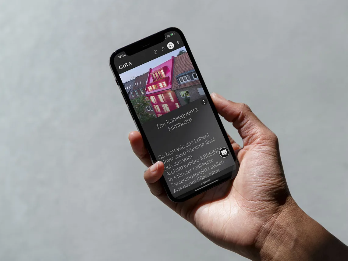 Smartphone-Ansicht einer Gira-Referenz-Detailseite mit dem Projekt Die konsequente Himbeere, einem pink gestrichenen Haus, auf hellgrauem Hintergrund