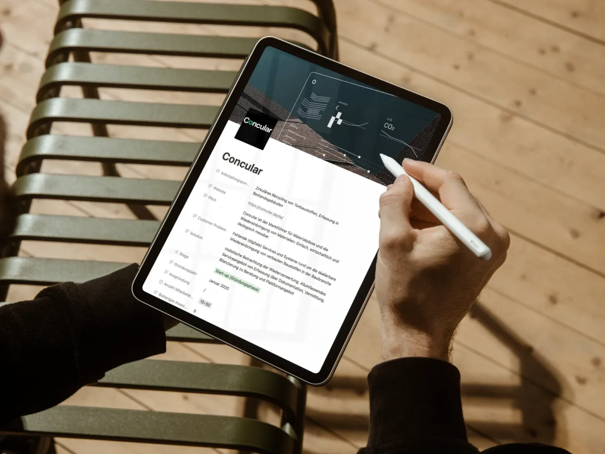 Hand hält ein iPad mit Apple Pencil, auf dem Bildschirm ist das Wienerberger Startup Canvas mit dem Profil des Startups Concular geöffnet.